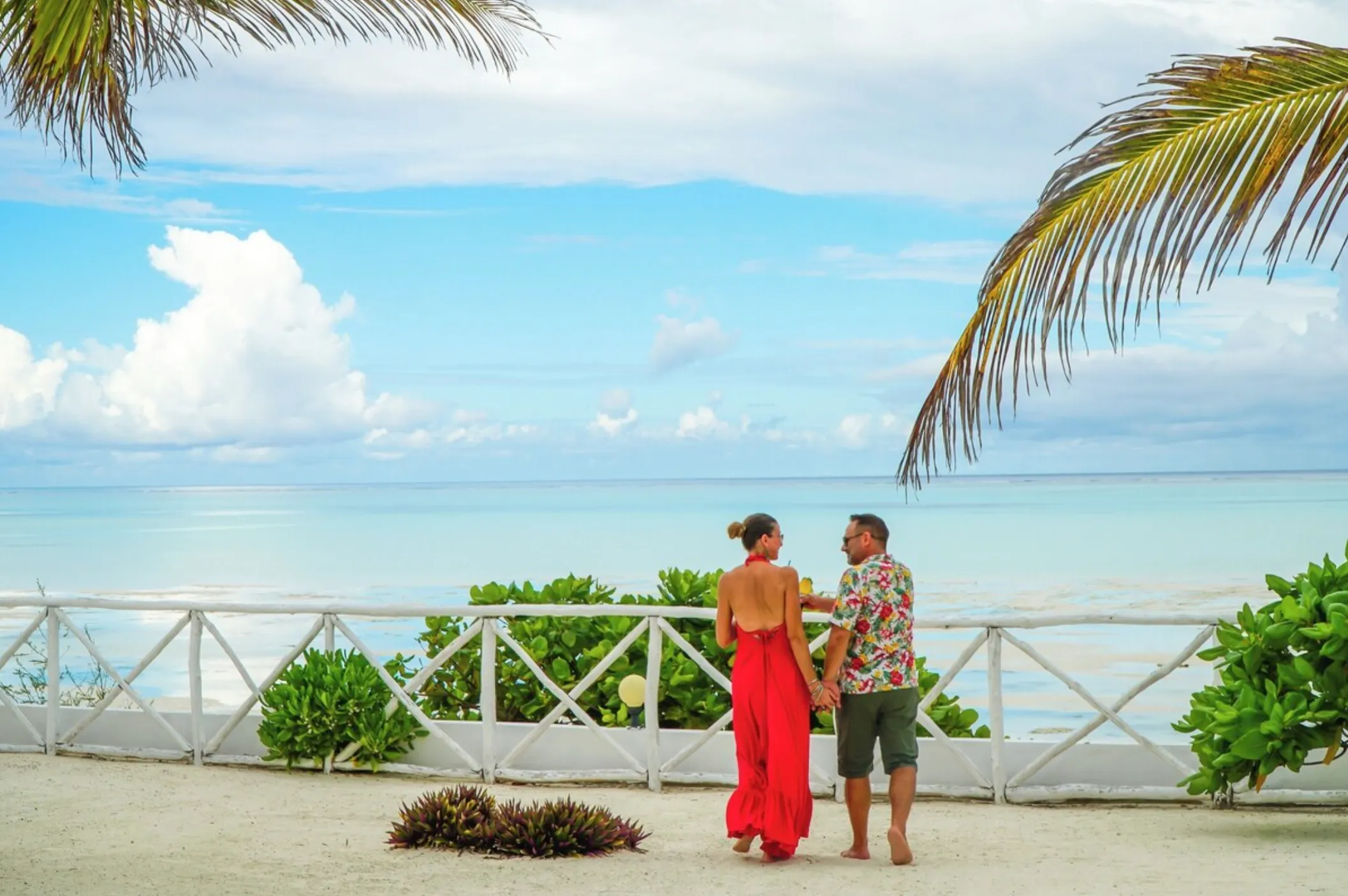 A couple sitting together on the low sea wall in front of the hotel, looking out over the lagoon at low tide.